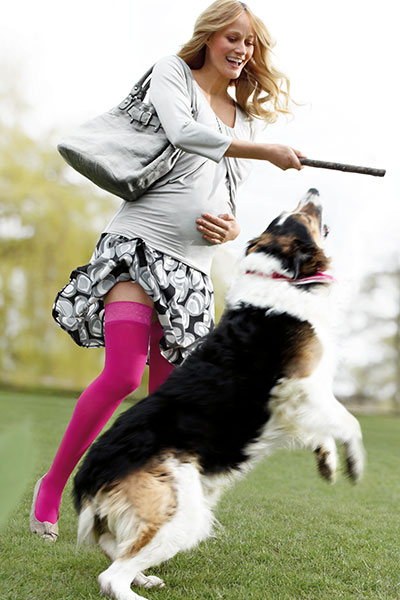 Lady wearing pink compression stockings playing with dog